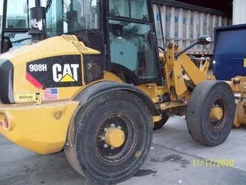 A yellow cat wheel loader parked in front of a building.