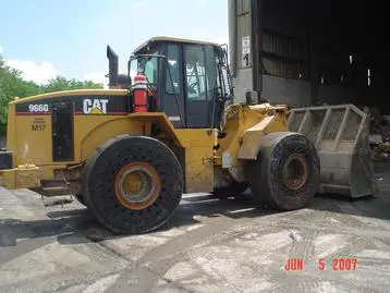 A large yellow cat wheel loader parked in front of a building.